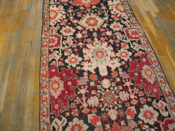Runner rug featuring a red, cream, and dark floral medallion pattern on light wooden floor planks.
