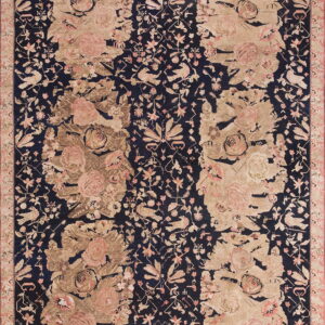 Navy blue rug with large beige and pink floral patterns, featuring distressed sections and small detailed birds.