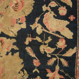 Low-pile rug detail showing a dark blue, gold, and pink floral pattern with a stylized bird motif.