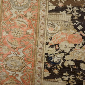 A floral patterned rug in dark brown, cream, and peach tones rests on light gray wood flooring.