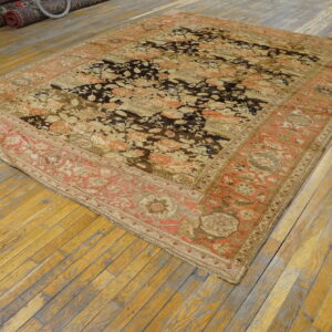Ornate low-pile rug in dark brown, tan, and coral sits on a weathered plank wood floor.