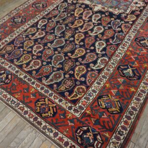 Navy and red patterned rug with a detailed paisley design lies on distressed light wood plank floors.