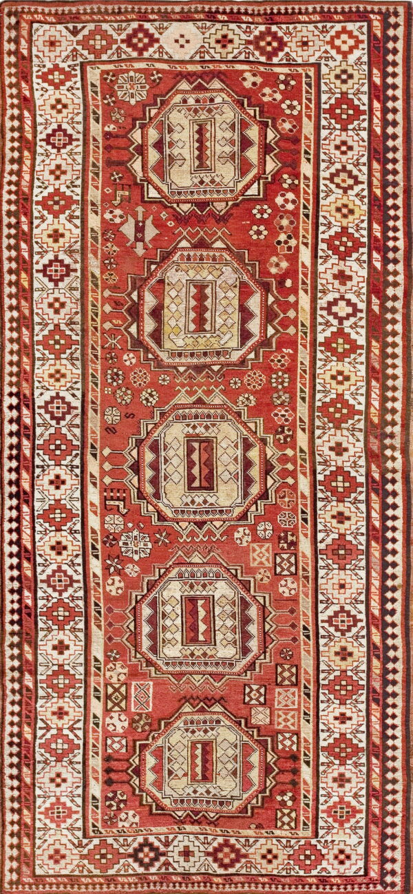 Rust and cream rug with a geometric pattern of repeating octagonal medallions and multiple ornate borders.