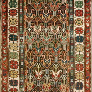 A complex rug featuring dark brown, red, and blue geometric motifs enclosed by multicolored floral borders on cream.