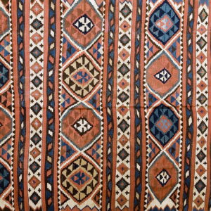 Rust and navy flatwoven rug displaying vertical columns of complex geometric diamond patterns.