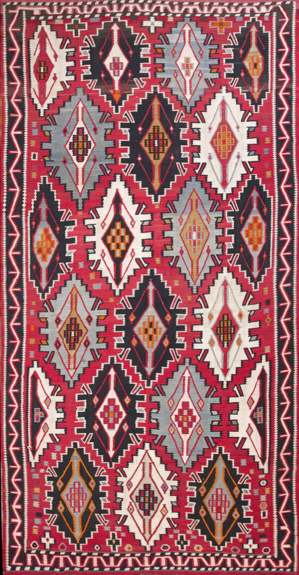 Geometric flatweave rug featuring large, stepped diamond medallions in red, black, white, gray, and orange accents.