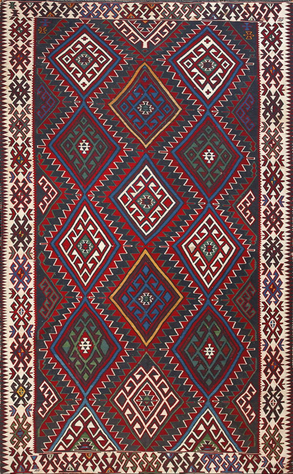 Multicolored flatweave rug featuring interlocking geometric diamonds in red, navy, white, and green.