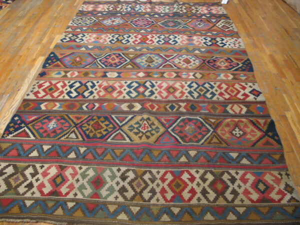 Multi-colored flatweave rug featuring geometric diamond and striped patterns on light hardwood planks.
