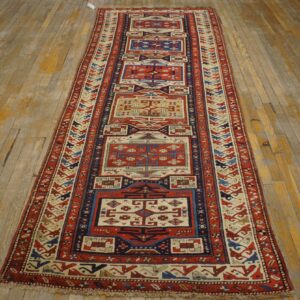 Geometric red and cream runner rug with blue accents sits on weathered light hardwood flooring.