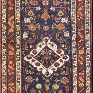 A narrow runner rug with a navy field and red border featuring traditional geometric medallions.