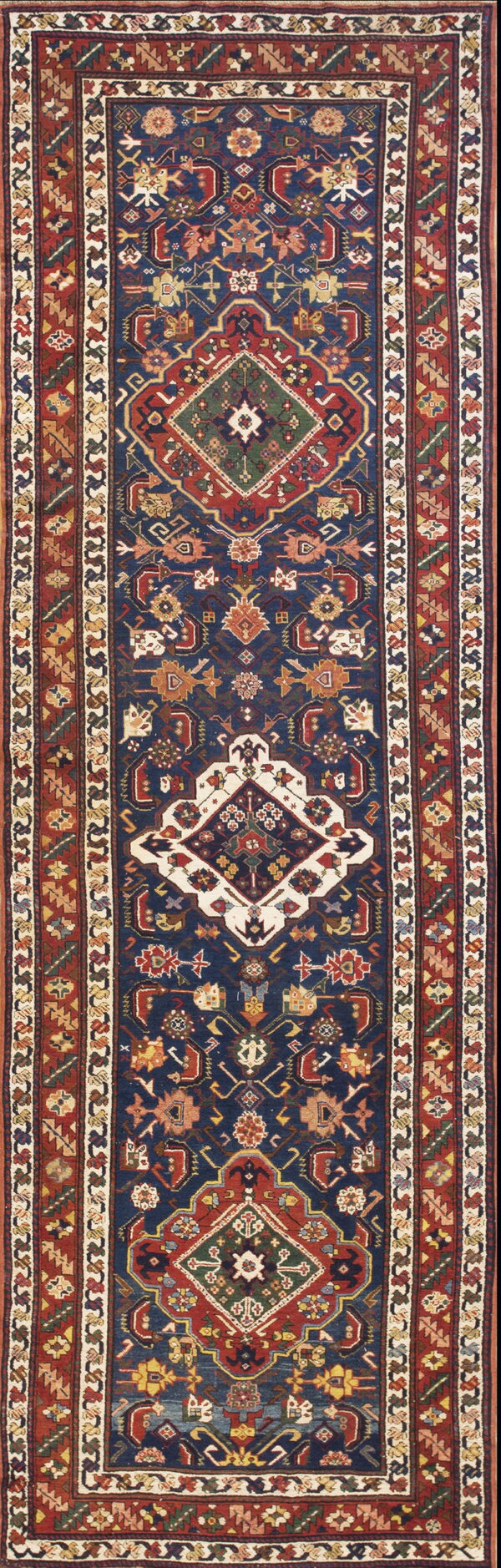 A narrow runner rug with a navy field and red border featuring traditional geometric medallions.