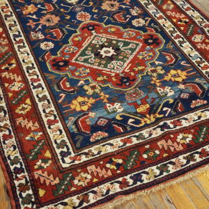 Navy and red medallion rug featuring detailed geometric patterns lies on a distressed wooden plank floor.