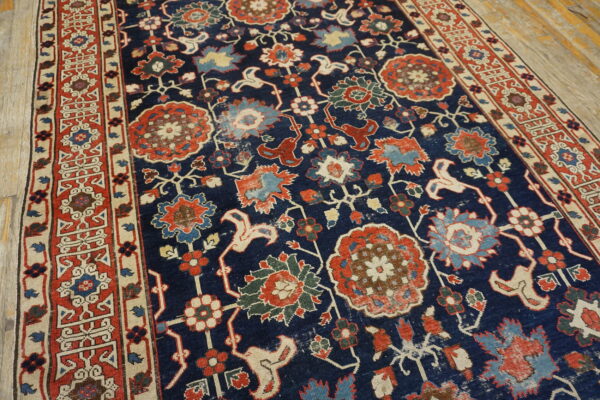 Traditional rug with a navy blue field and ornate red, blue, and cream floral patterns on light wood floors.