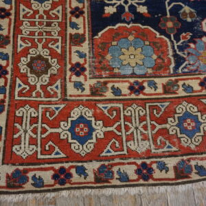 Traditional red, navy, and cream rug with geometric and floral patterns on distressed wood plank flooring.