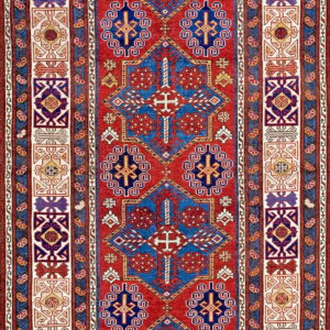 Red rug with large blue geometric medallions and wide, colorful, contrasting patterned borders.