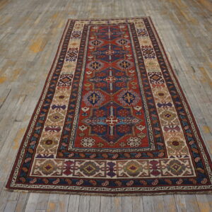 Geometric runner rug in red, navy, and cream with multiple ornate borders on distressed wood planks.