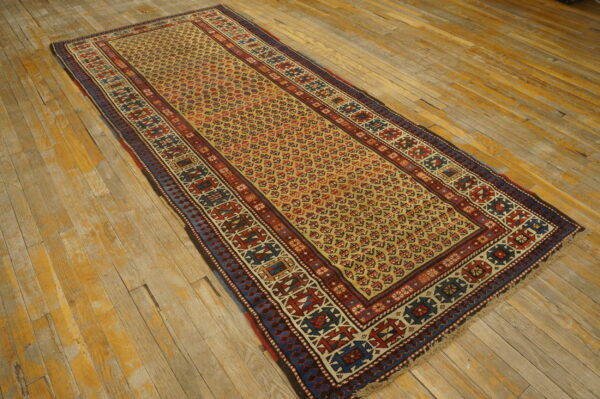Runner rug with red, blue, and yellow geometric patterns displayed on rustic, wide plank wood flooring.