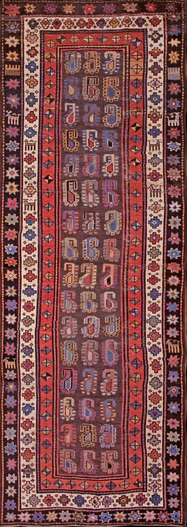 Dark, low-pile runner rug with colorful repeating tribal symbols, framed by red, cream, and dark geometric borders.