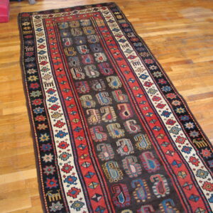 Dark runner rug featuring vibrant red, blue, and cream geometric patterns rests on a honey-toned wood floor.