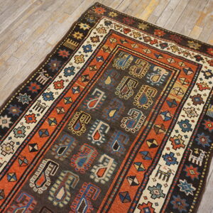 Dark brown and rust tribal rug featuring blue and cream medallions and borders on light plank flooring.