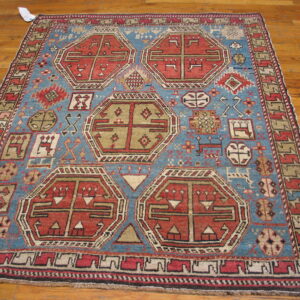 Geometric red and tan hexagonal medallions decorate a blue tribal rug on hardwood flooring.