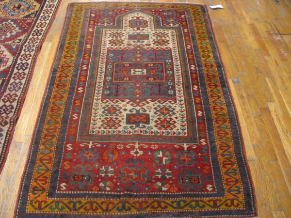 Geometric red runner with ivory, blue, and gold tribal patterns rests on light hardwood planks.