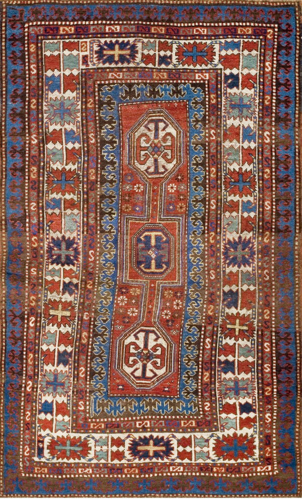 Intricately patterned low-pile rug dominated by deep red, cobalt blue, brown, and cream geometric tribal motifs.