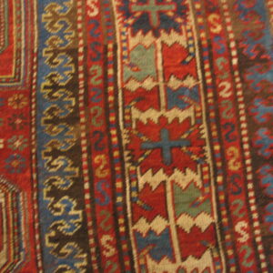 Red, blue, and ivory geometric tribal patterns form detailed vertical borders on a low-pile rug.
