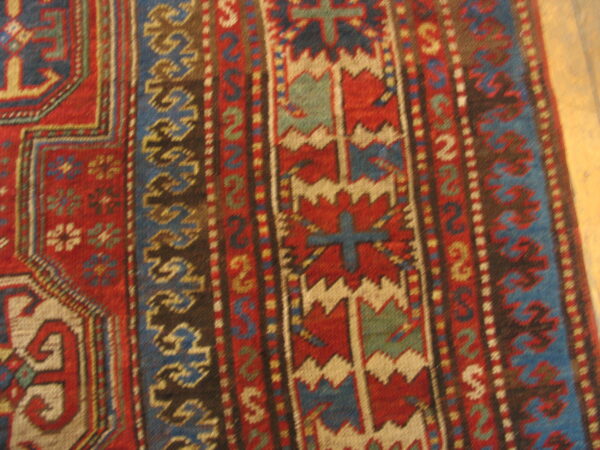 Red, blue, and ivory geometric tribal patterns form detailed vertical borders on a low-pile rug.