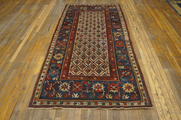 Geometric runner rug in deep red and blue with cream accents placed on distressed wood flooring.