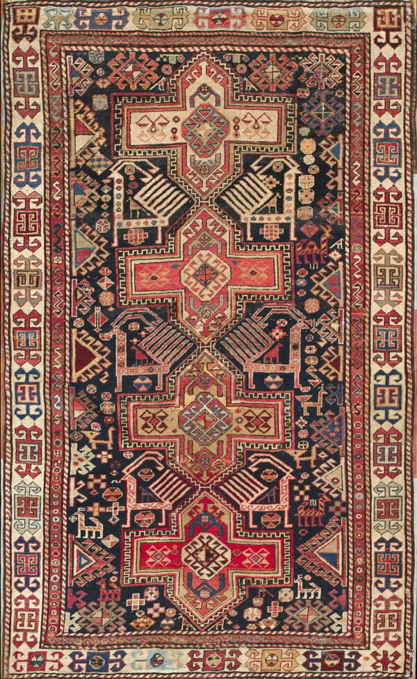 Low pile rug featuring a complex geometric pattern with a navy field and borders of red, beige, and gold.