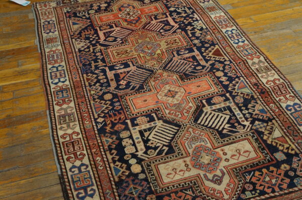 Deep blue and rust geometric rug with intricate patterns displayed on a natural wood floor.