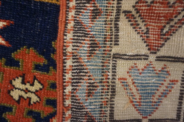 Textured close-up contrasts navy pile patterns with an adjacent beige flatweave featuring geometric designs in red and blue.