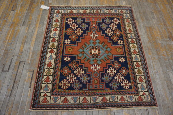 Navy and terracotta geometric rug with complex patterns placed on a worn, gray wood floor.