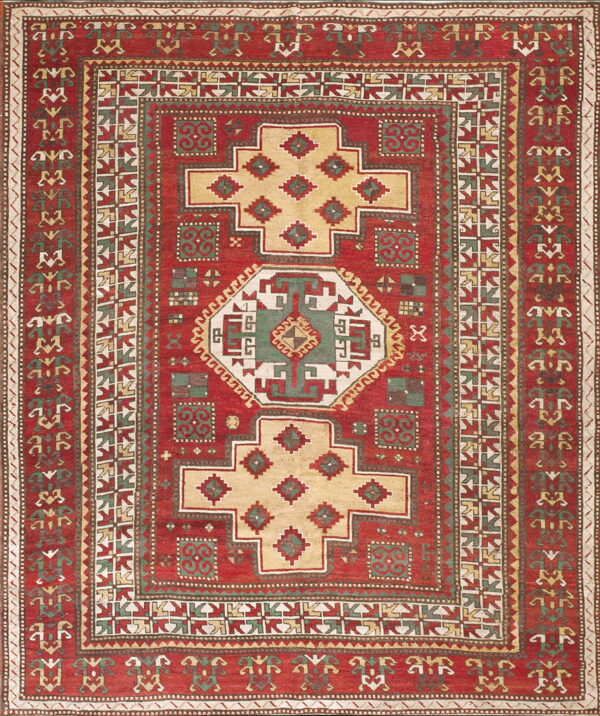 Red geometric rug featuring large stepped diamond patterns in tan, dark green, and cream.