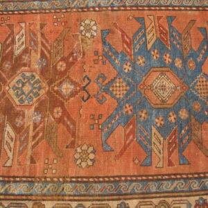 Geometric tribal rug detail featuring a rust field with contrasting blue and brown stylized star motifs and patterned borders.