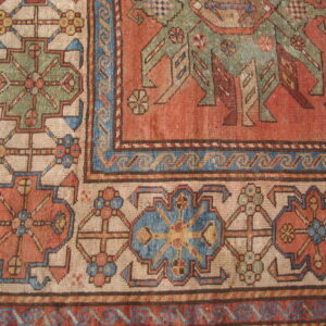 Detailed view of a low pile rug featuring rust, cream, blue, and green geometric motifs and borders.