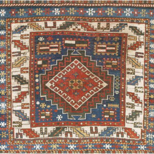 A detailed geometric rug in navy, red, and cream featuring a complex central diamond and ornate borders.