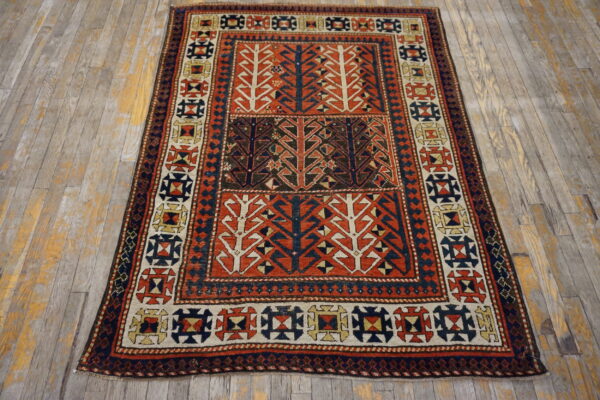 Geometric low-pile rug in rust, navy, and cream with stylized tree motifs on distressed wood.