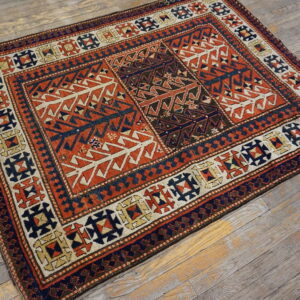 Geometric rug in deep rust, navy, and cream colors on a distressed gray wooden floor.