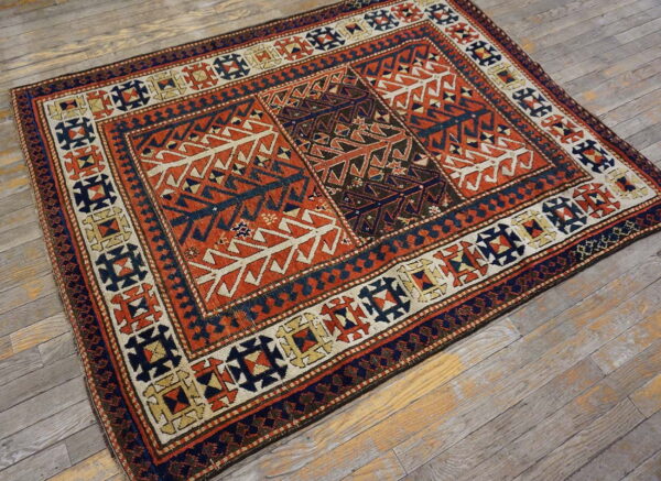 Geometric rug in deep rust, navy, and cream colors on a distressed gray wooden floor.