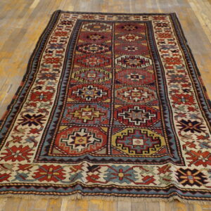 A runner rug featuring complex red, blue, cream, and gold geometric medallions rests on distressed wood flooring.