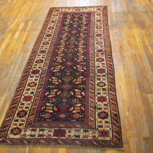 Red, navy, and beige tribal runner rug featuring geometric designs on a distressed plank hardwood floor.
