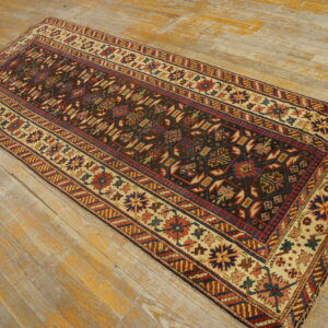 Geometric runner rug in dark brown, red, and beige lies on weathered wooden floor planks.