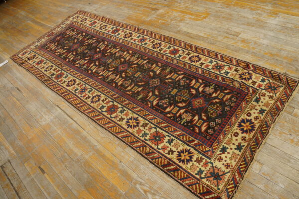 Geometric runner rug in dark brown, red, and beige lies on weathered wooden floor planks.