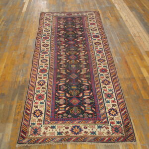 Geometric runner rug with a dark field and colorful borders sits on an aged wooden plank floor.