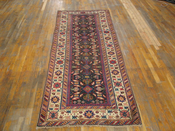 Geometric runner rug with a dark field and colorful borders sits on an aged wooden plank floor.