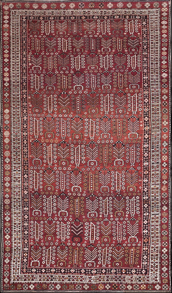 A vertically oriented rug with a dark red field and repeating ivory geometric motifs surrounded by patterned borders.