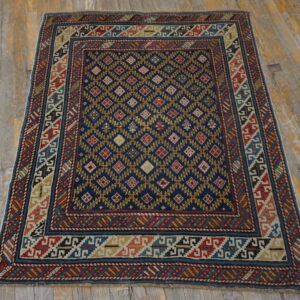 Navy, red, and gold geometric rug with intricate borders lying on distressed wood floorboards.