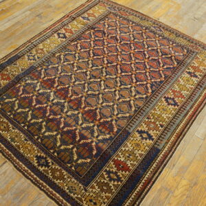 Navy blue, rust, and gold geometric rug with multiple borders displayed on wide plank wood floors.